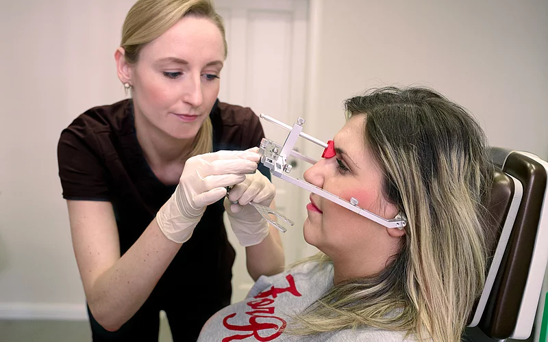 Die Zahnärztin führt eine Funktionsdiagnostik bei einer Patientin durch.